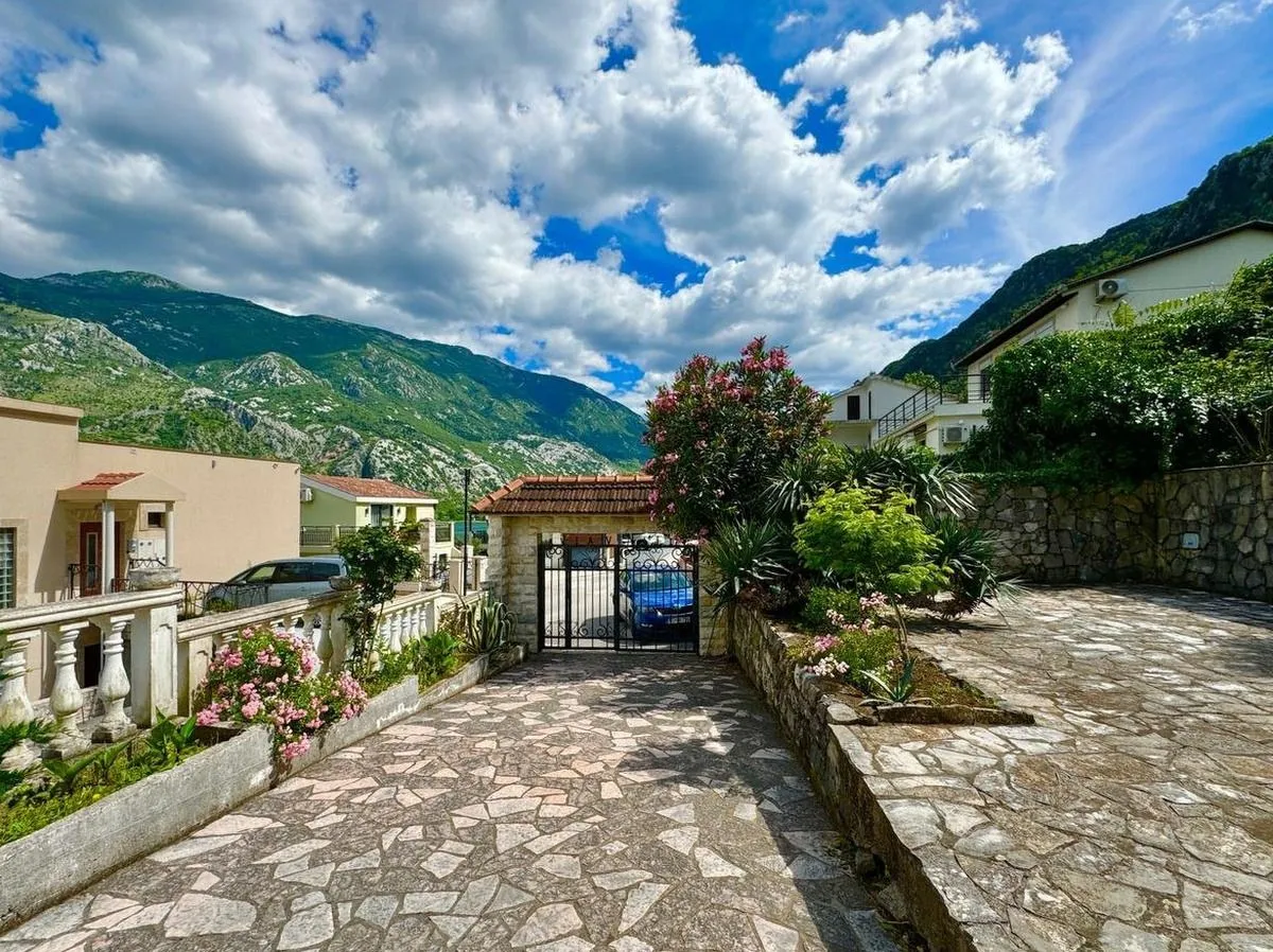 Dvorište sa popločanim prilazom, kapijom i pogledom na planine.