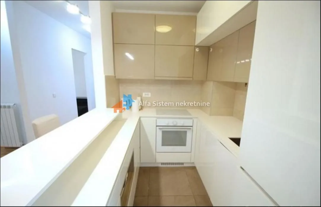 Kuhinja opremljena belim elementima i šankom.