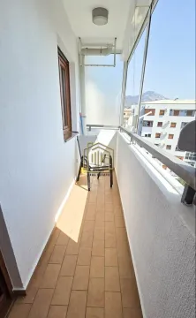 Dugačak zastakljeni balkon sa keramičkim pločicama i stolicom. - image 10