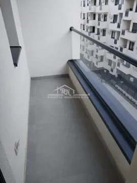 Uska popločana terasa sa staklenom ogradom i pogledom na susednu zgradu. - image 14
