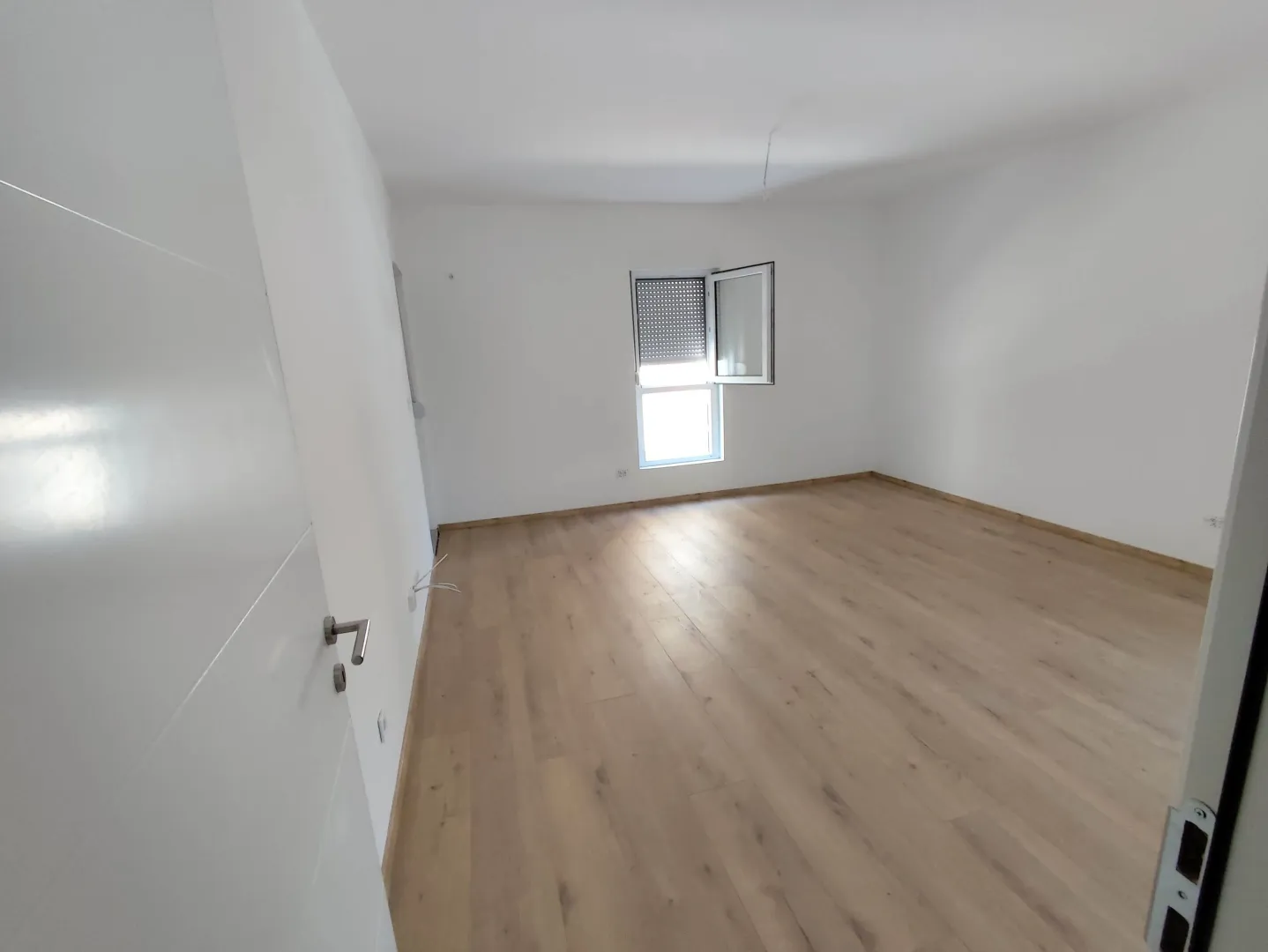 Empty unfurnished room with white walls and wooden flooring.