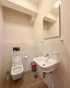 Small bathroom with white tiles, toilet, and a sink with a mirror. - image 7