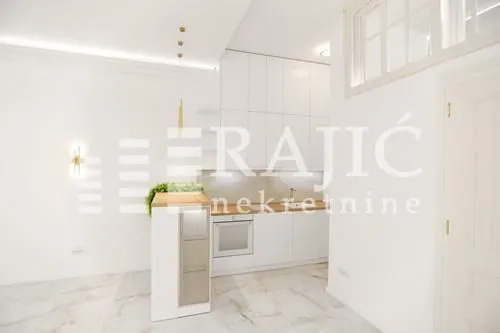 Modern white kitchen with a bar counter within a bright interior.