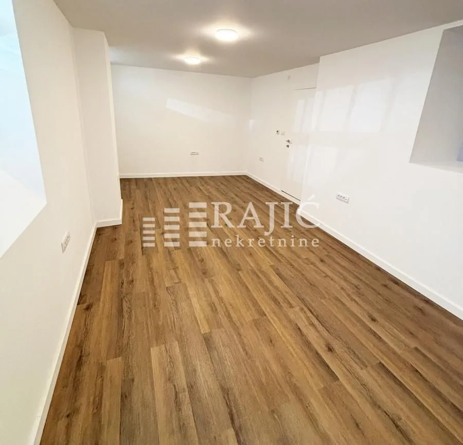 Empty room with laminate flooring and white walls.