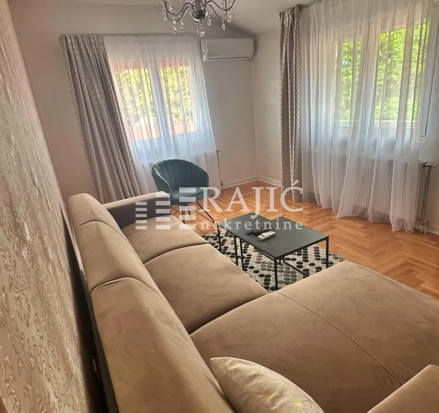Living room with a sofa, coffee table, and windows with curtains.
