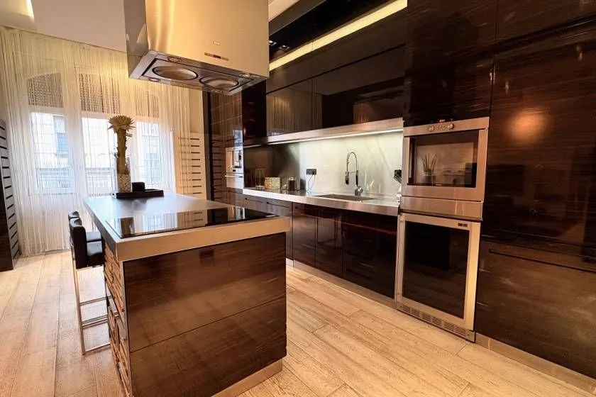 Modern kitchen with an island, dark cabinetry, and built-in appliances.