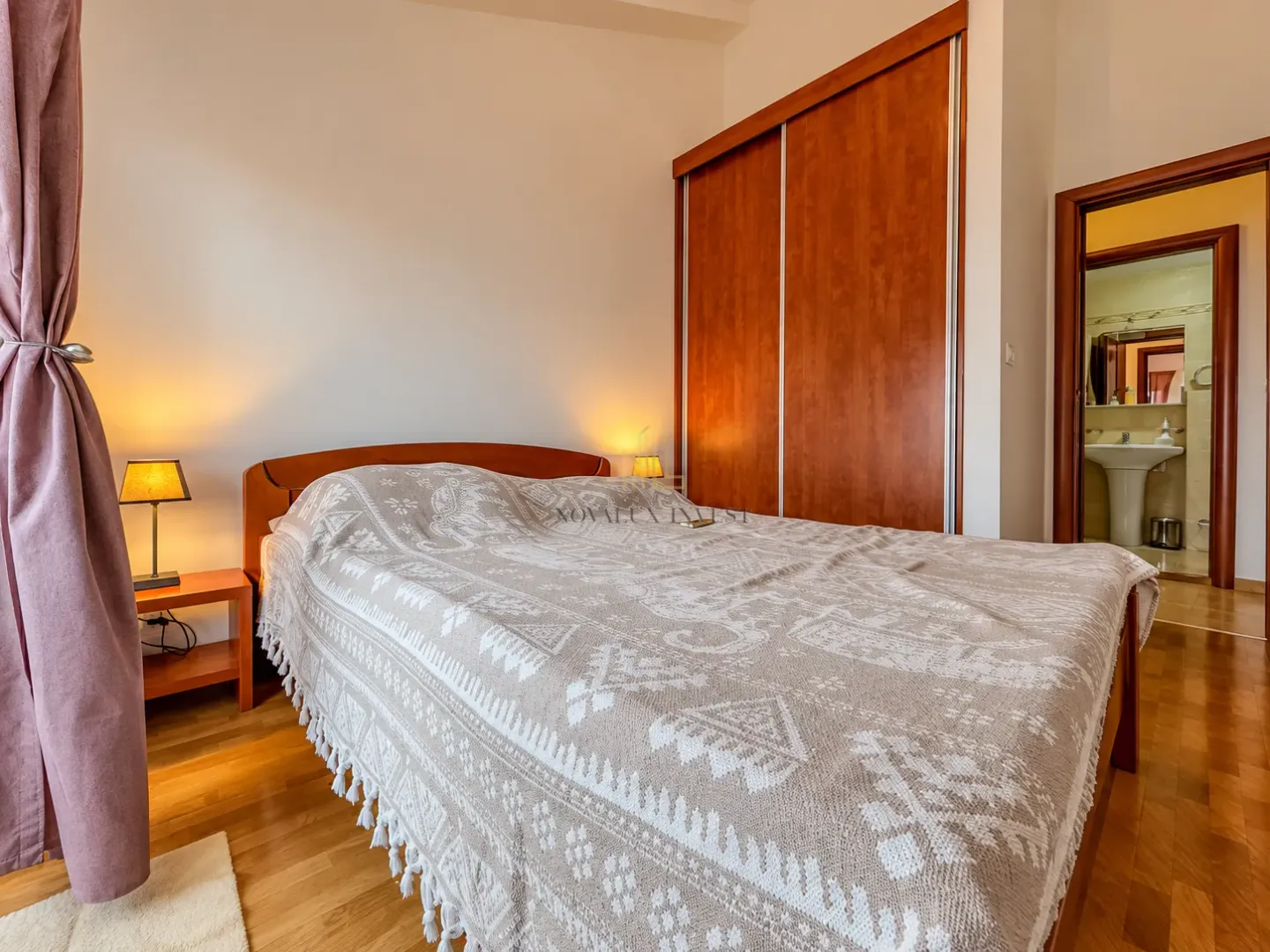 Bedroom with a double bed, wooden wardrobe, and a view of the bathroom.