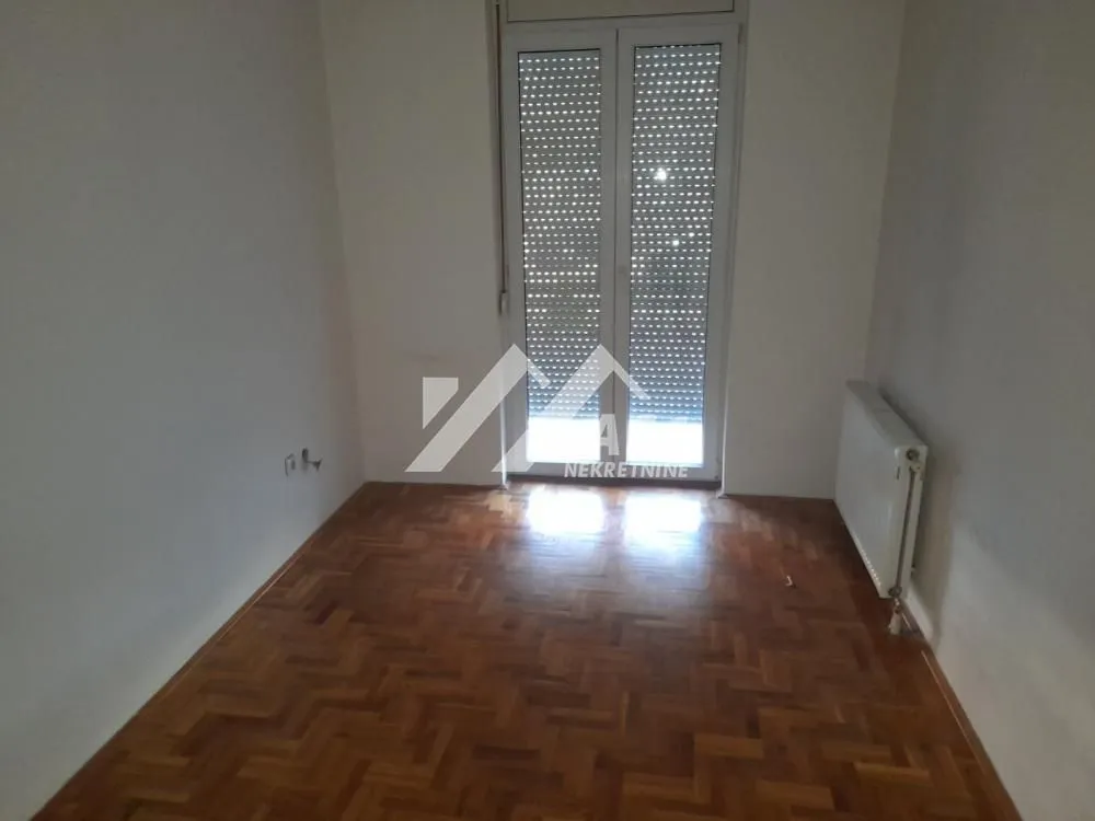 Empty room with hardwood flooring and balcony doors.
