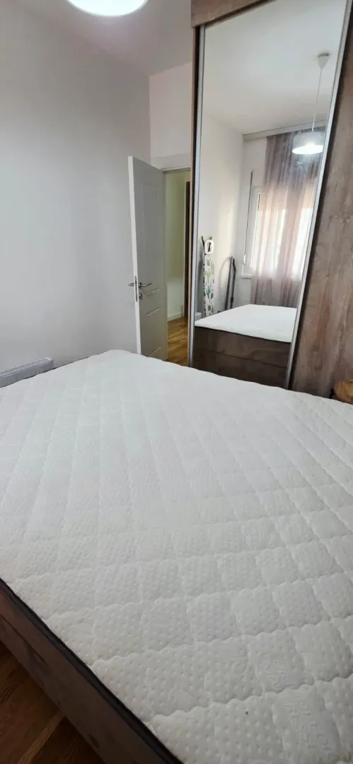 Spavaća soba sa krevetom i ugradnim ormarom sa ogledalom.