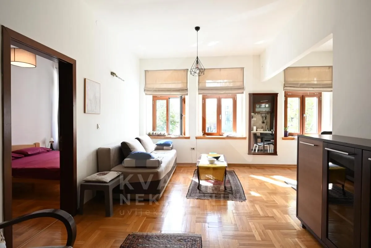 Living room with a sofa, parquet flooring, and windows.