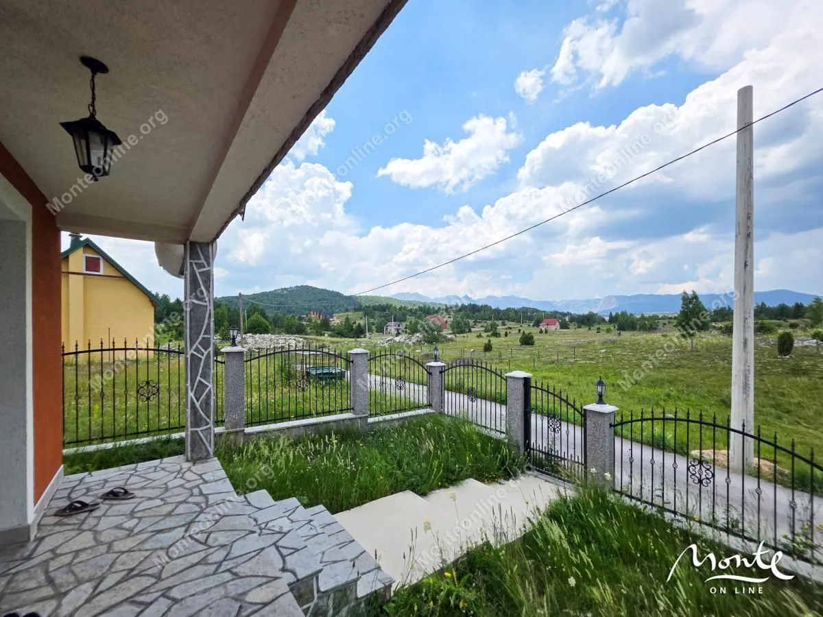 Pogled sa popločane terase na dvorište i okolne planine.
