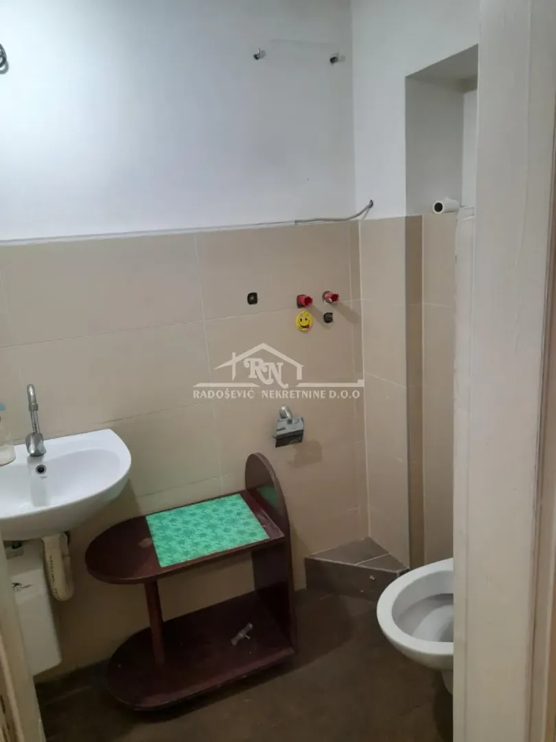Small bathroom with a sink and toilet in light tiles.