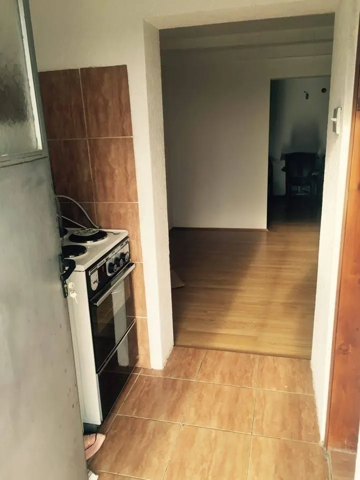 Pogled na ulazni dio sa šporetom koji vodi u prazne prostorije sa laminatom.