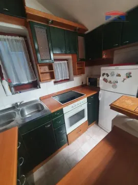 Manja kuhinja sa tamnozelenim elementima, drvenim radnim površinama i ugrađenom rernom. - image 3