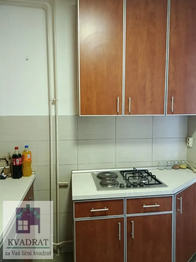 Manja kuhinja sa drvenim elementima i ugradnom pločom.