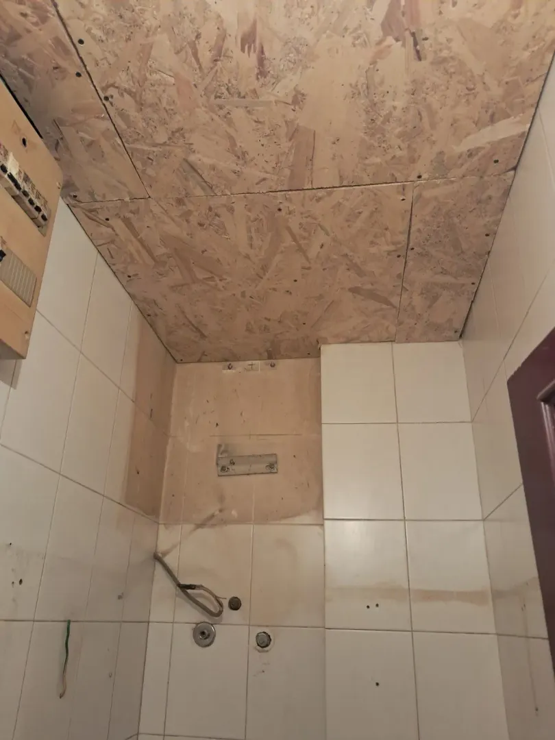 Bathroom under renovation with tiles and OSB board ceiling.