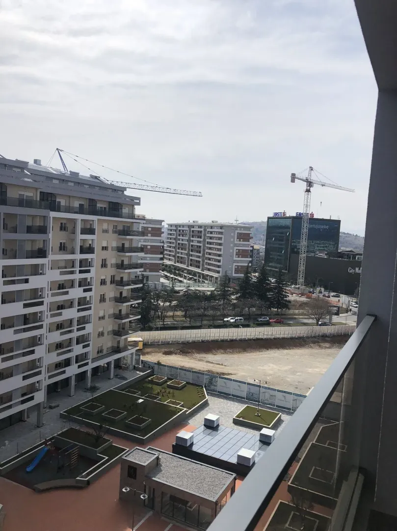 View from the balcony overlooking a modern residential complex and landscaped courtyard.