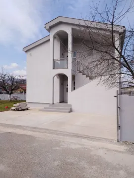 A two-story house with a light facade and a paved yard. - image 4