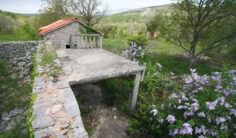 Pogled na staru kamenu kuću sa dvorištem i zelenilom u okruženju. - image 11