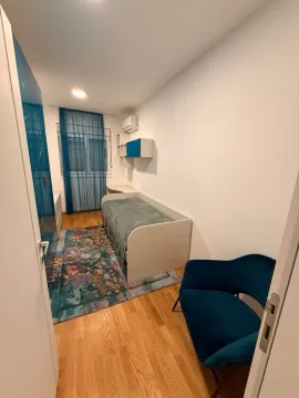 Manja spavaća soba sa krevetom, plavom foteljom i garderoberom. - image 8