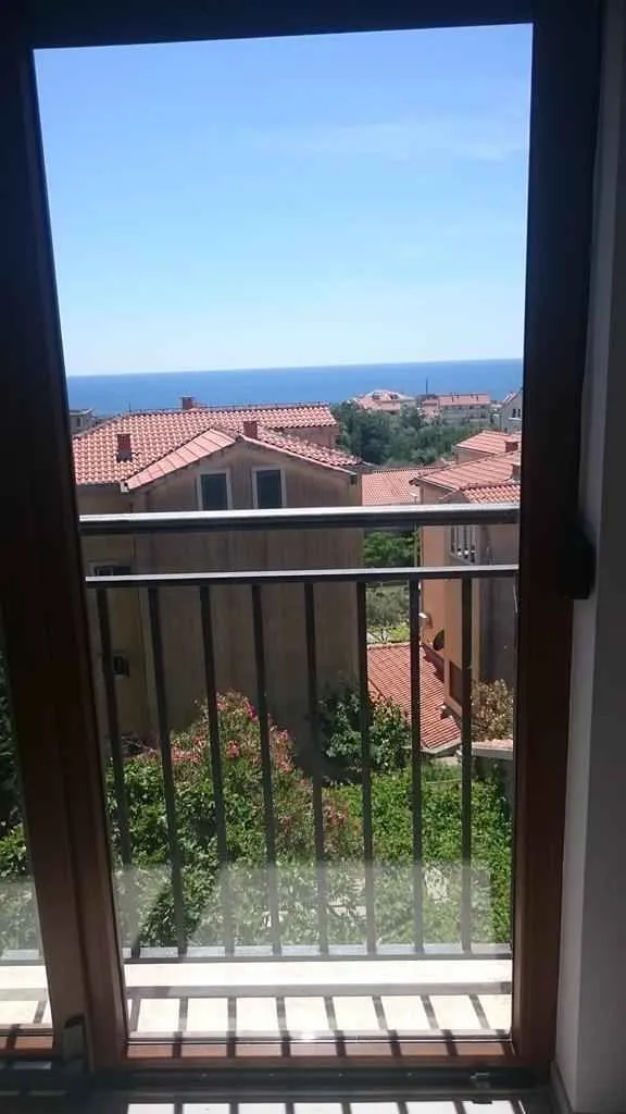 Pogled na more i okolne krovove kroz balkonska vrata.
