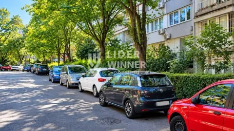 Pogled na parking ispred stambene zgrade sa parkiranim automobilima i zelenilom. - image 9