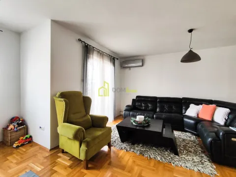 Living room with a black sectional sofa, a green armchair, and a coffee table. - image 2