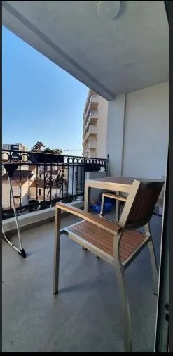 Namtještena terasa sa stolom i stolicom i pogledom na okolne zgrade.