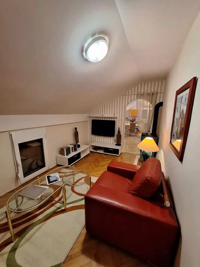 Attic living room with a red leather armchair and a television.
