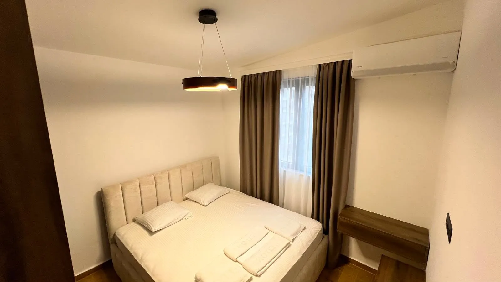 Furnished bedroom with a double bed, curtains, and air conditioning.