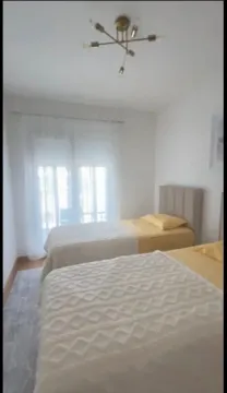 Svijetla spavaća soba sa dva kreveta i balkonskim vratima. - image 5