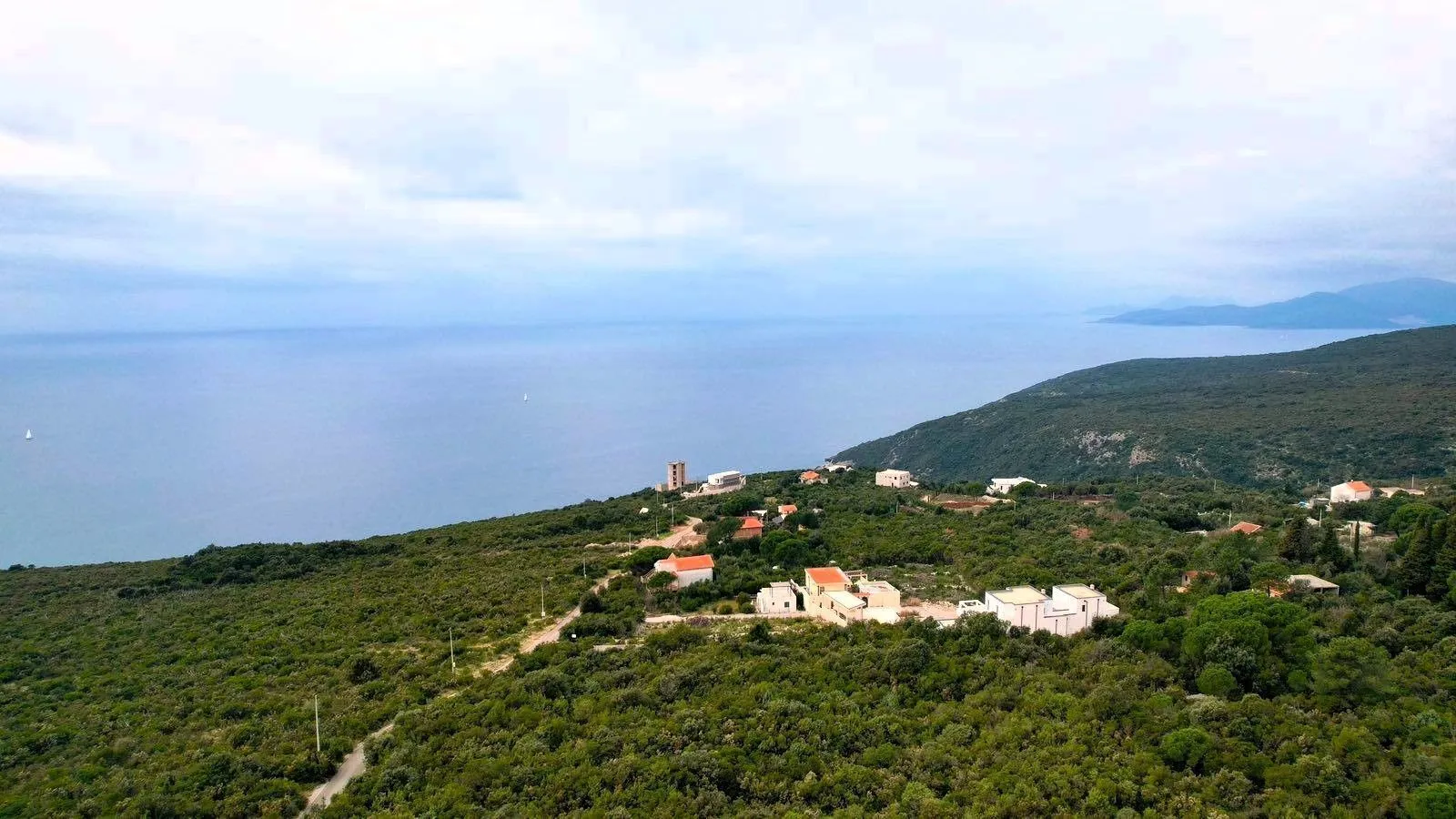 Pogled iz vazduha na obalu i okolno naselje sa zelenilom.