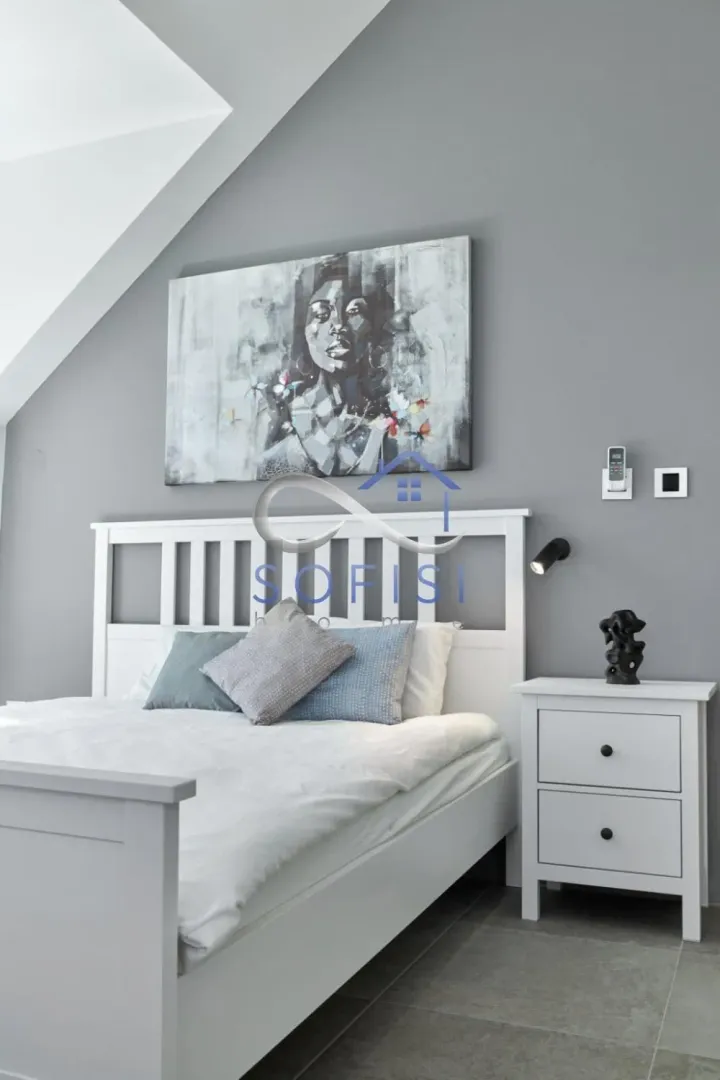 Modern bedroom with a white bed and an artwork on the wall.