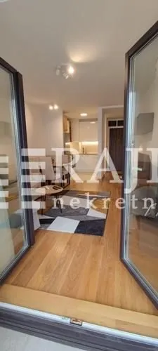 View from the doorway towards the living room and dining area with hardwood flooring.