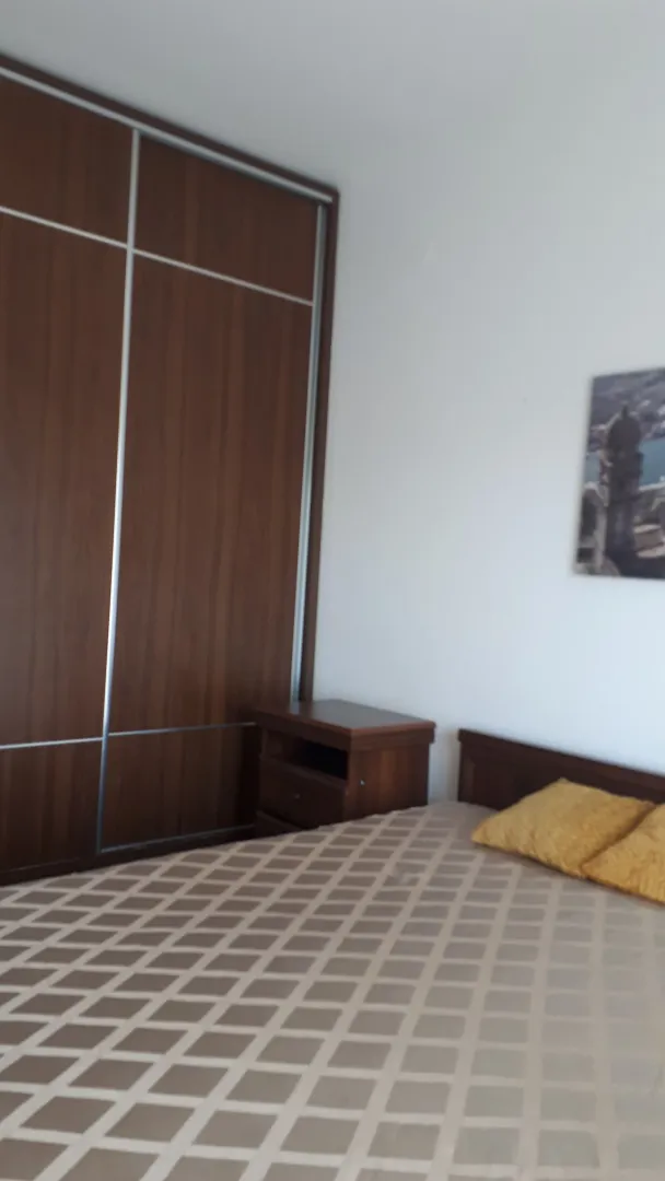 Furnished bedroom with a double bed, wardrobe, and a nightstand.