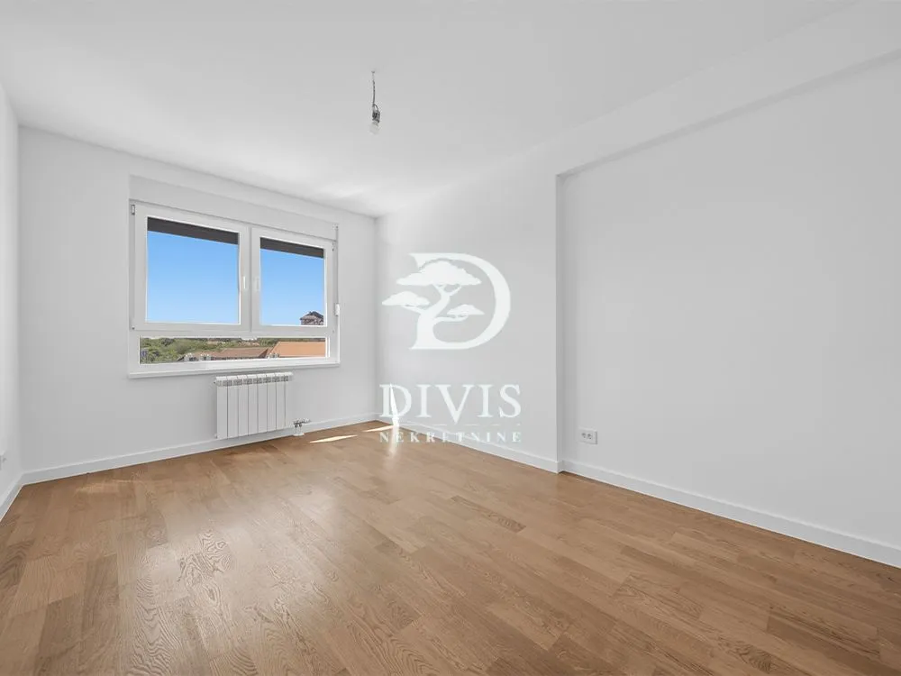 Empty room with white walls, wooden parquet flooring, and a window.
