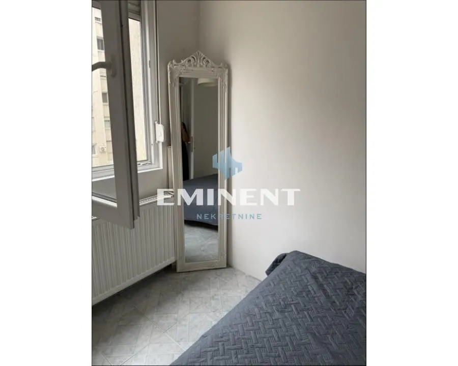 Small bedroom with a bed, a mirror, and a window.