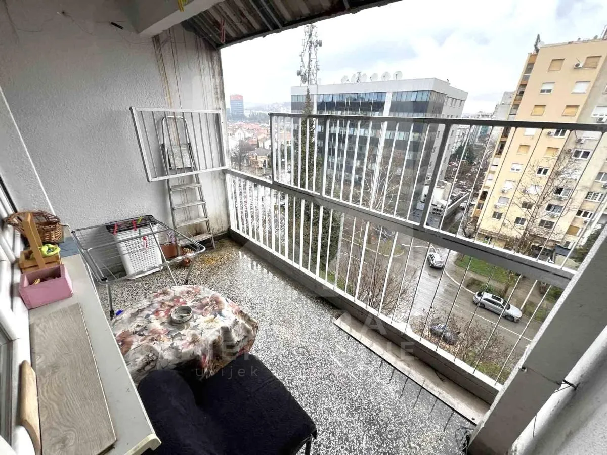 Covered balcony with metal railing and city view.