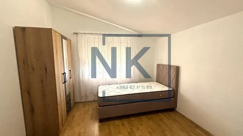 Bedroom with a bed, wardrobe, and window.