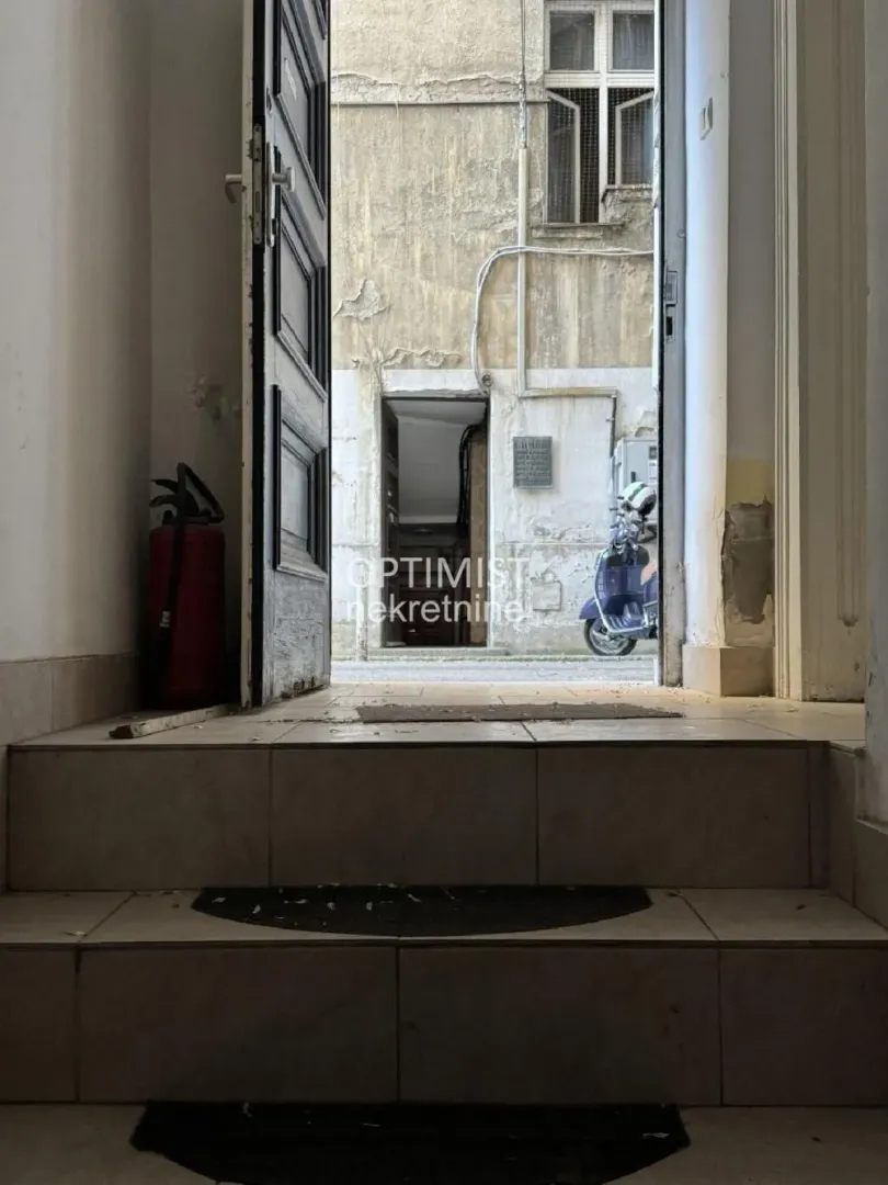 Pogled iz ulaza zgrade na dvorište i skuter.