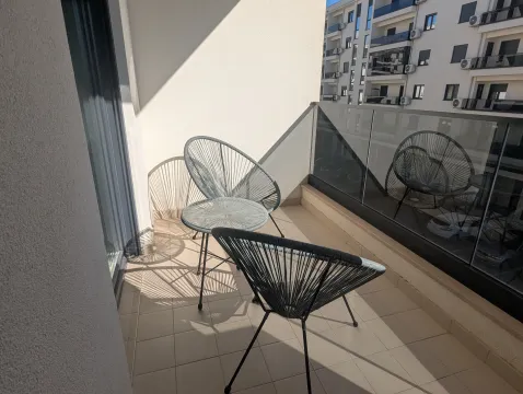 Furnished balcony with two chairs, a small table, and a view of the building. - image 11