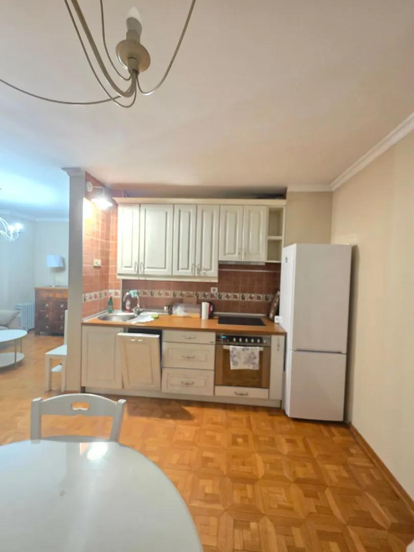Manja kuhinja sa bijelim elementima i trpezarijskim stolom u prvom planu.