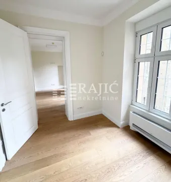 Empty room with hardwood floors and a window, looking through a doorway into another room. - image 3