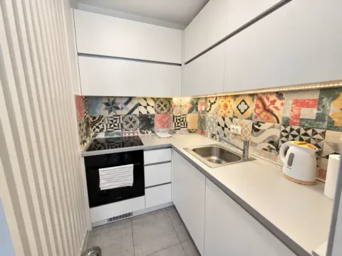 Small kitchen with white cabinets and colorful tiles. - image 15