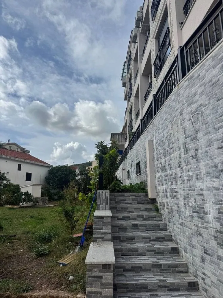 Stepenište koje vodi prema ulazu u zgradu sa popločanim dvorištem.