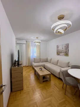 Living room with a sectional sofa, wooden parquet flooring, and modern chandeliers. - image 7