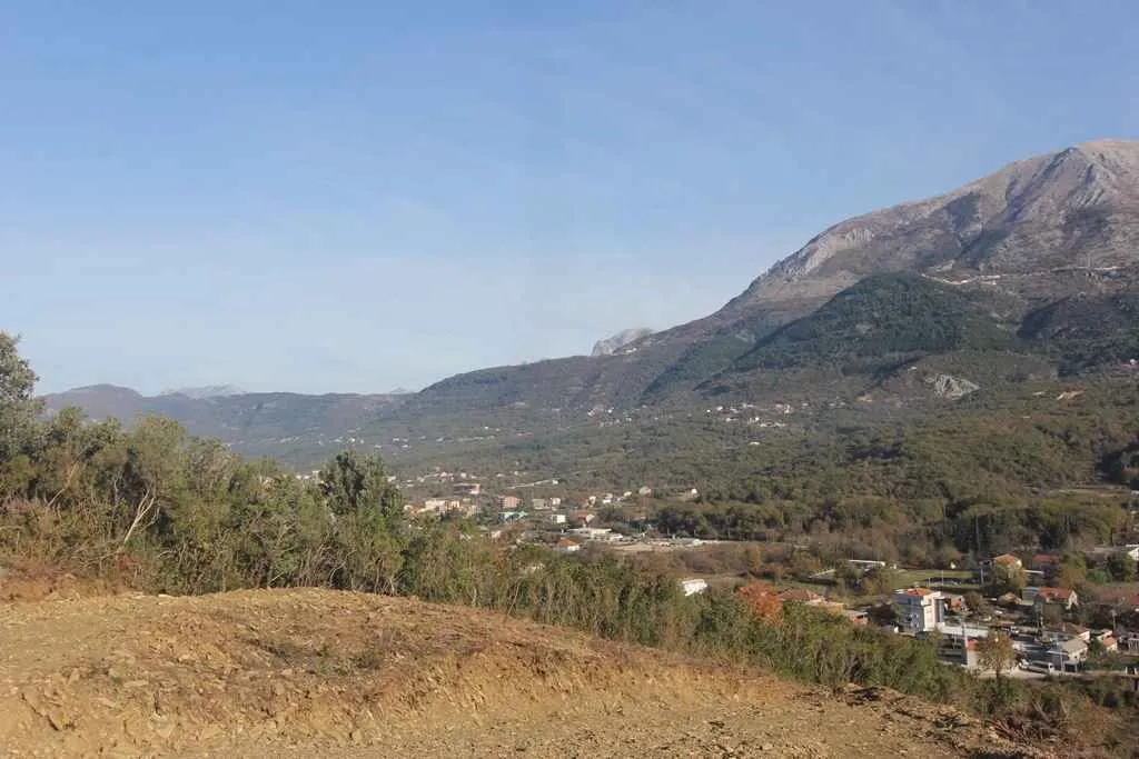 Pogled sa uzvišenja na planine i naselje u dolini.
