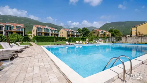 Veliki vanjski bazen sa ležaljkama i pogledom na stambeni kompleks i okolne planine. - image 2