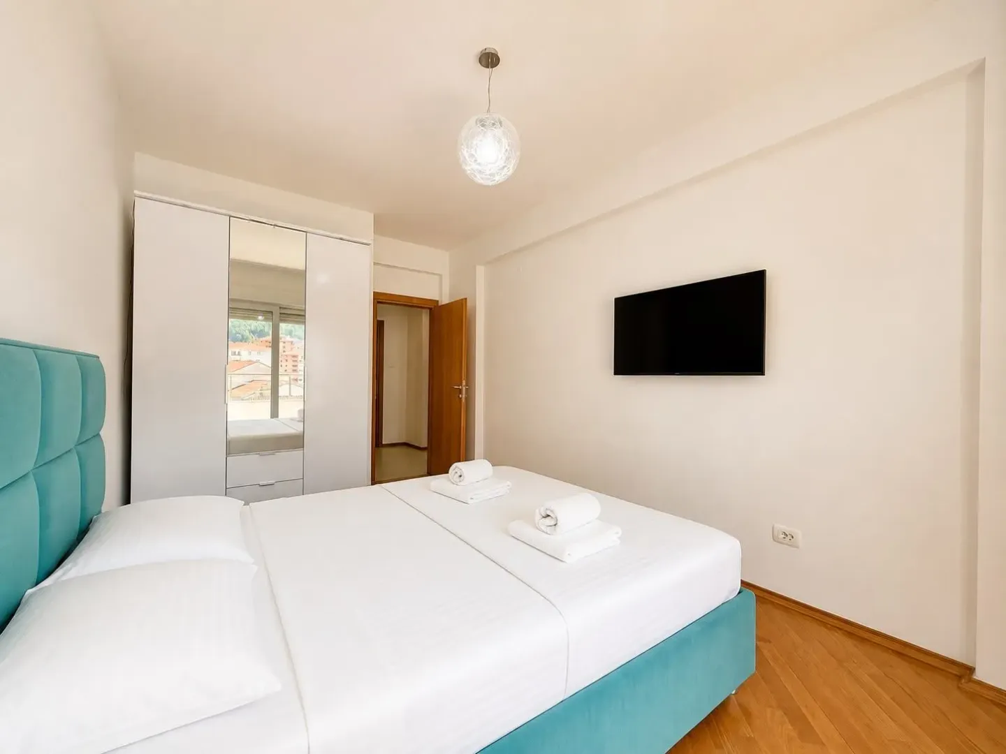 Modern bedroom with a double bed, wardrobe, and television.