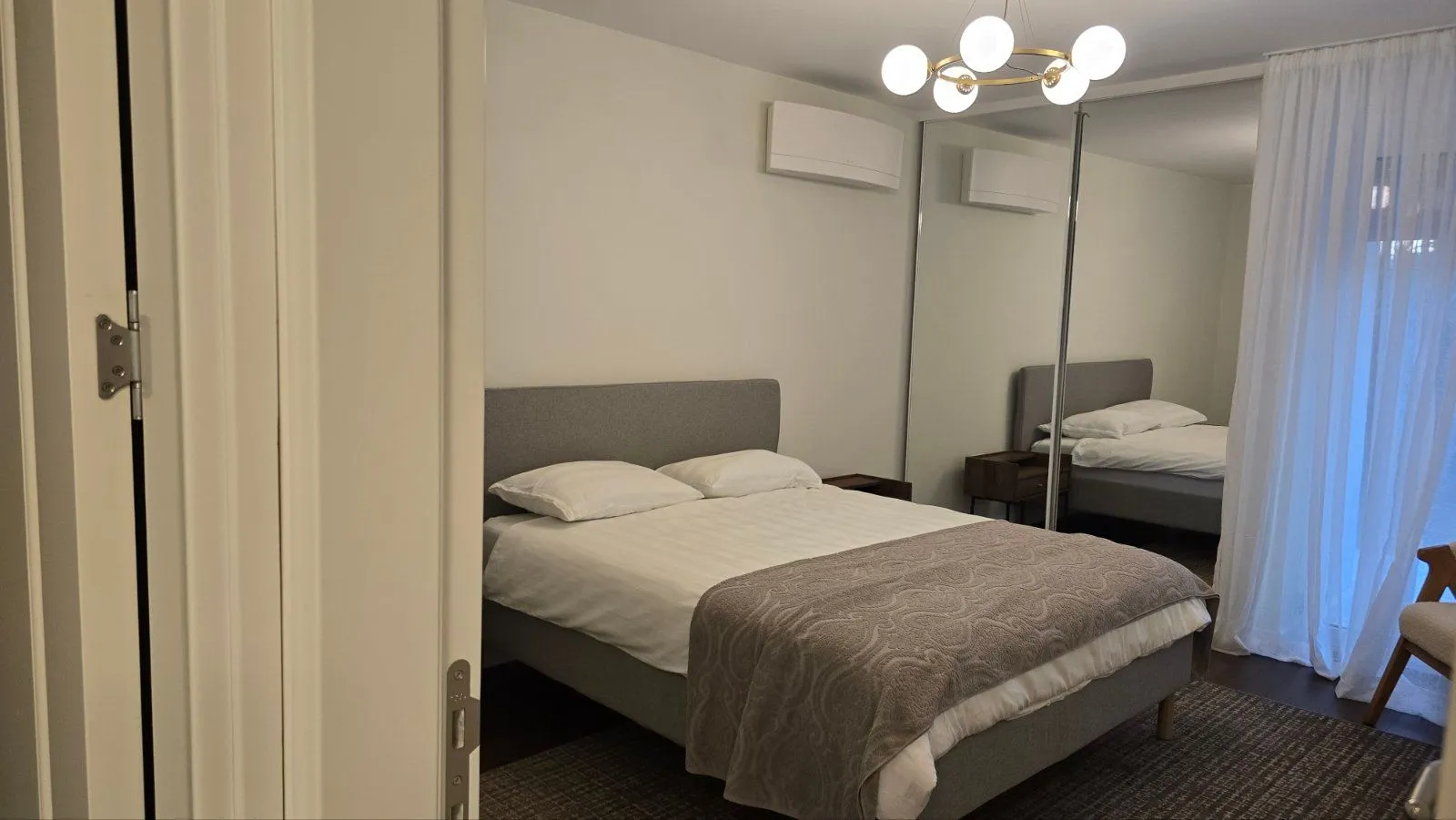 Furnished bedroom with a double bed and a mirrored built-in wardrobe.